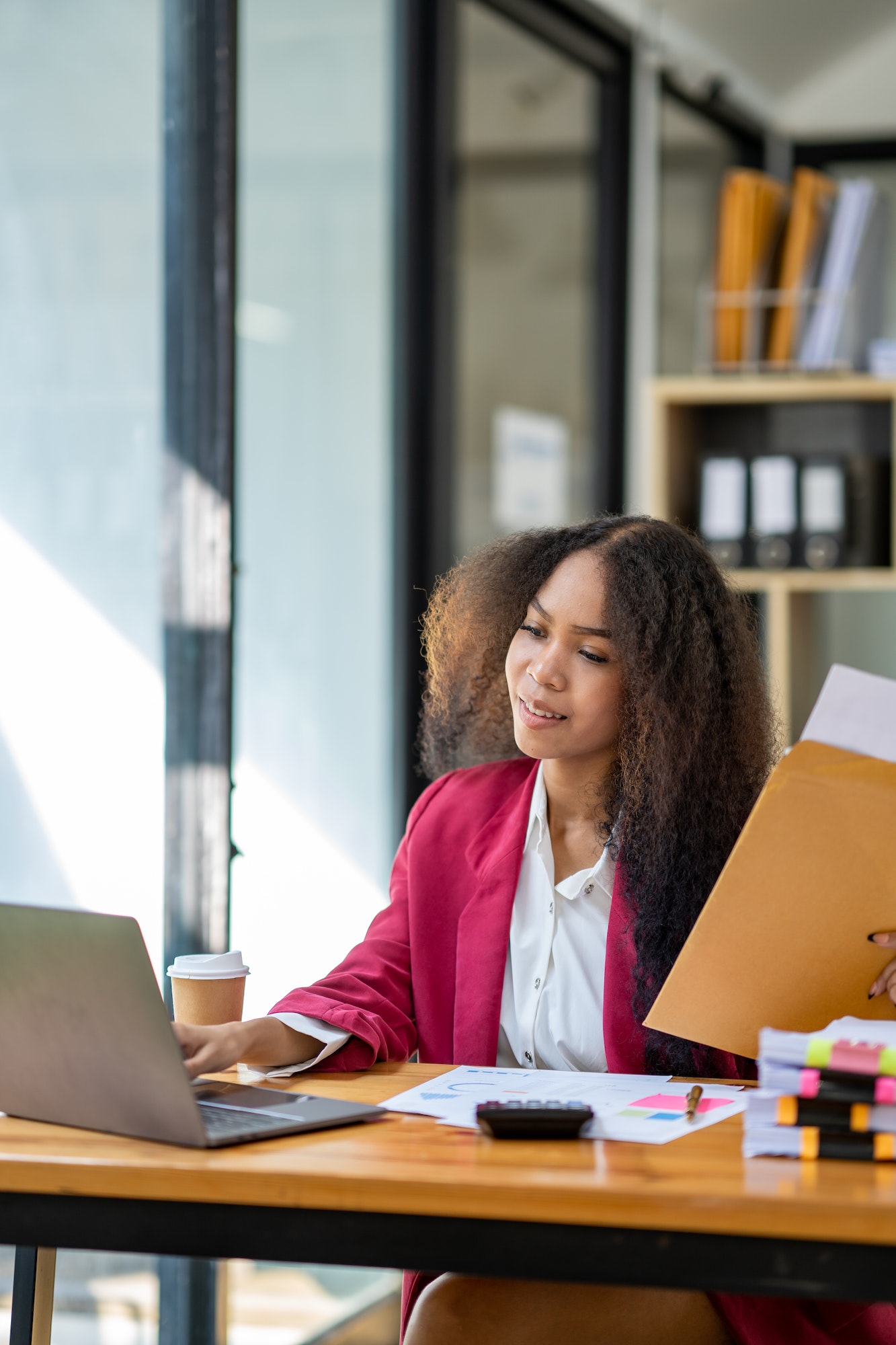 An African businesswoman holds a brown envelope on a table and opens a sheet of business information